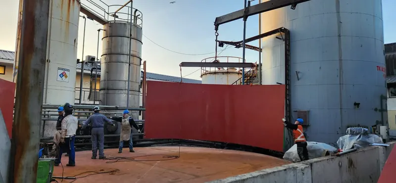 Operarios instalando una placa metálica de gran tamaño en una planta