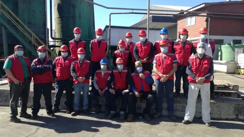 Equipo completo de operarios con casco y ropa de seguridad en planta