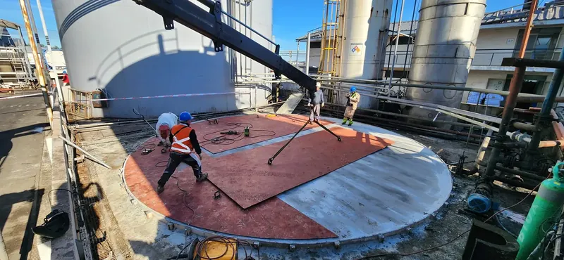 Operarios instalando una tapa metálica circular sobre un tanque