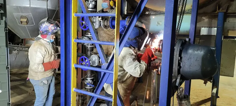 Soldador trabajando en una estructura metálica dentro de la planta