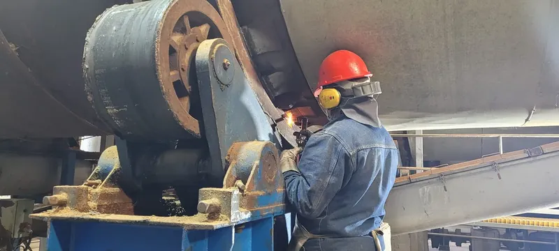 Operario reparando un equipo industrial con protección auditiva y ocular