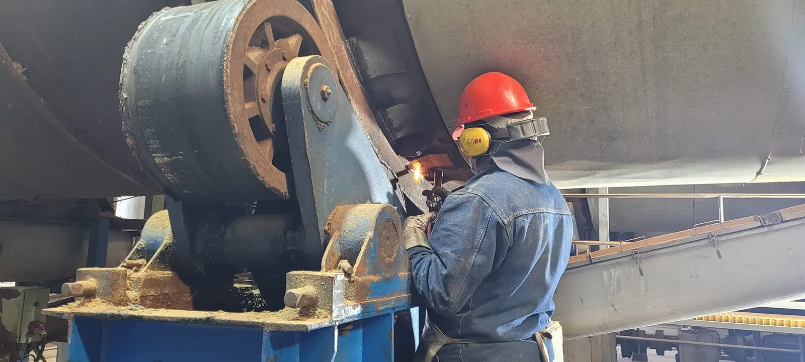 Operario con casco, protección auditiva y ocular reparando un equipo industrial